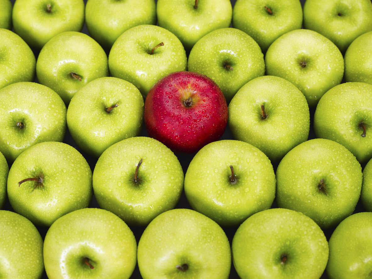 A single red apple among green apples representing Zonio uniquness